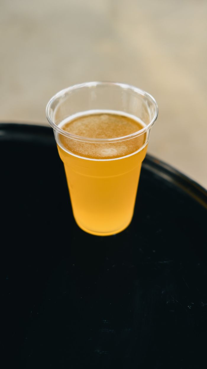 A clear plastic cup filled with refreshing golden beer on a dark surface.
