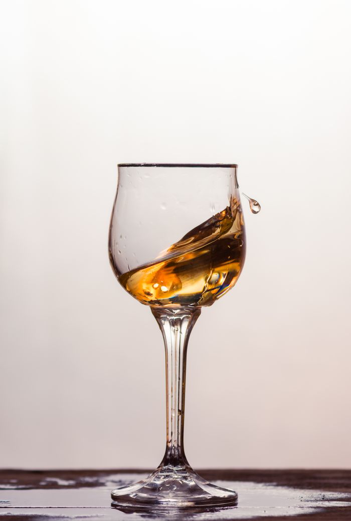 About A clear glass with swirling amber liquid against a soft background.