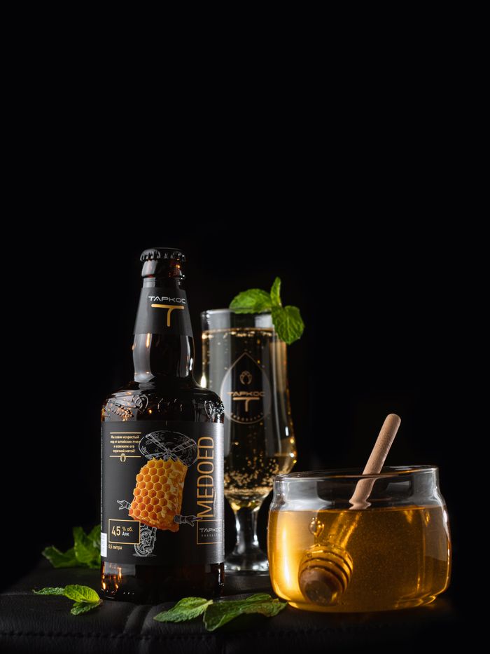 Home Elegant still life featuring craft mead with honey and mint leaves on a dark background.